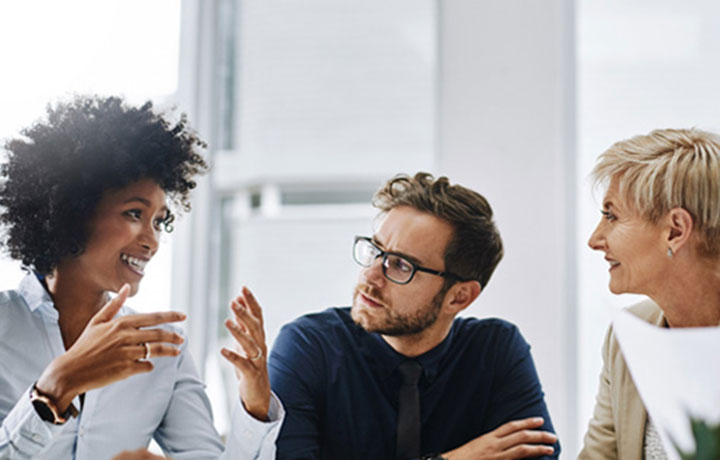 Three people sitting at a table having an animated discussion